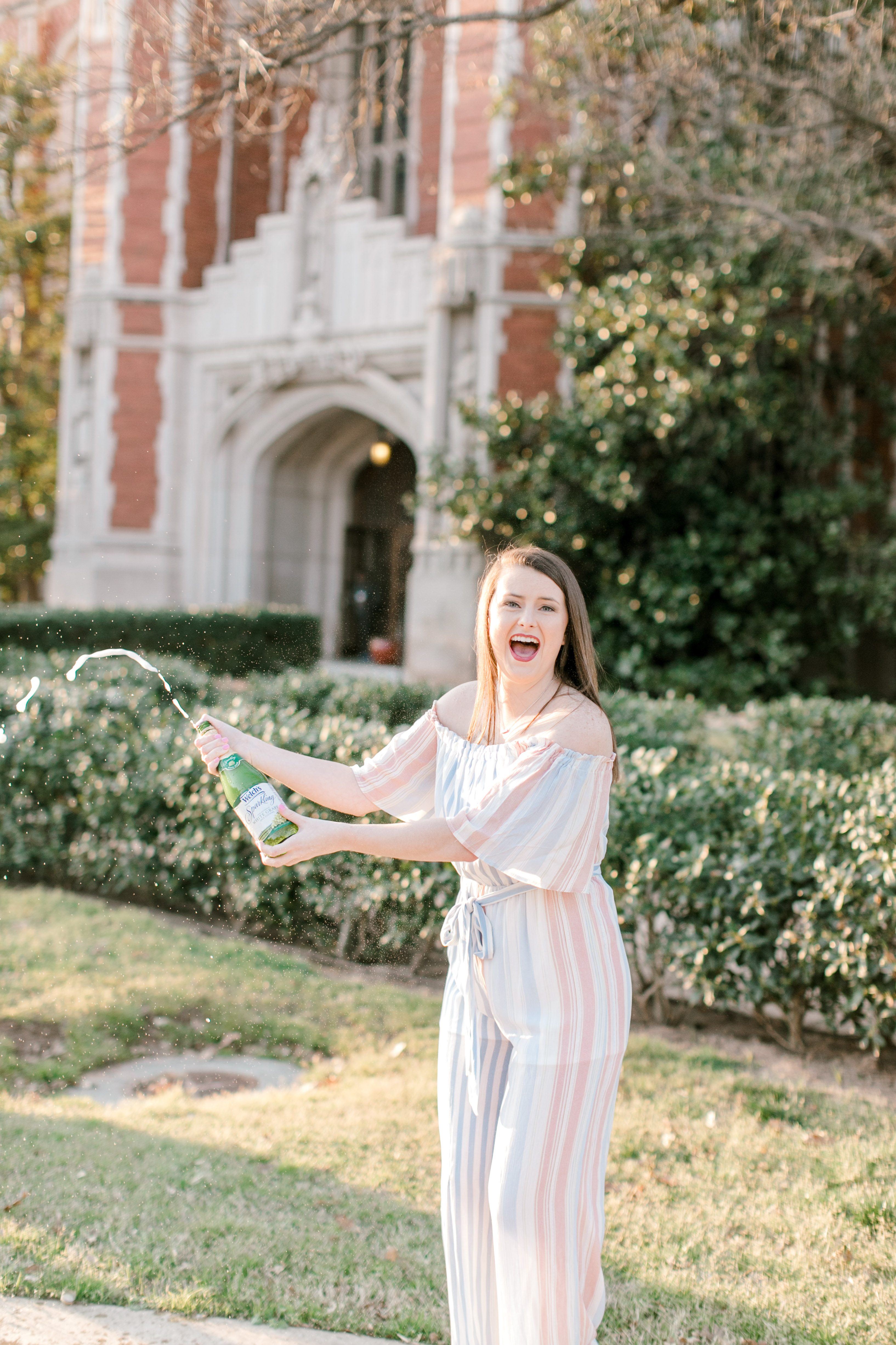 ou senior taking celebratory photos by popping bottle of sparkling cider in front of the bizz