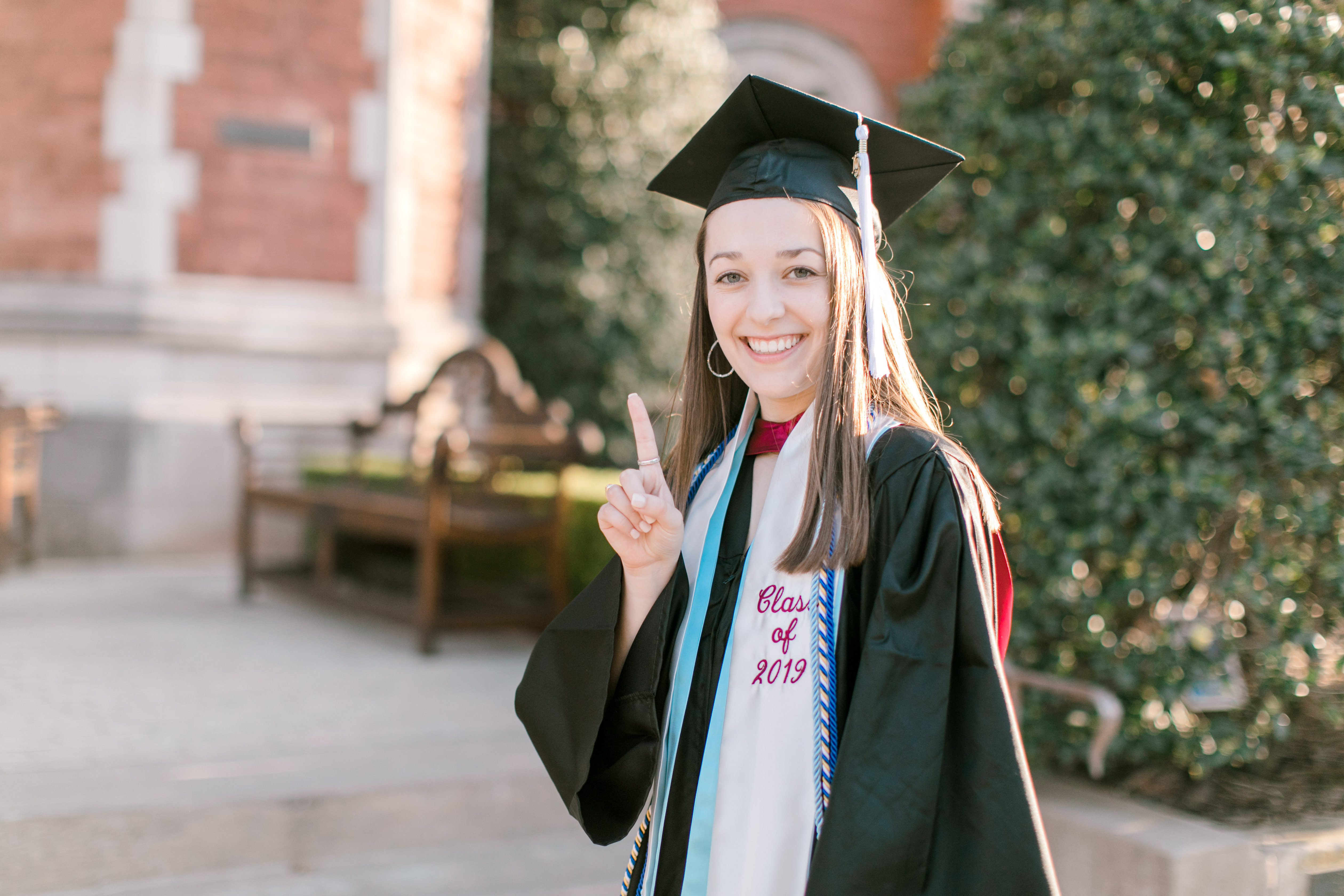 ou senior holds up a number 1 with her hand in cap and gown graduation regallia