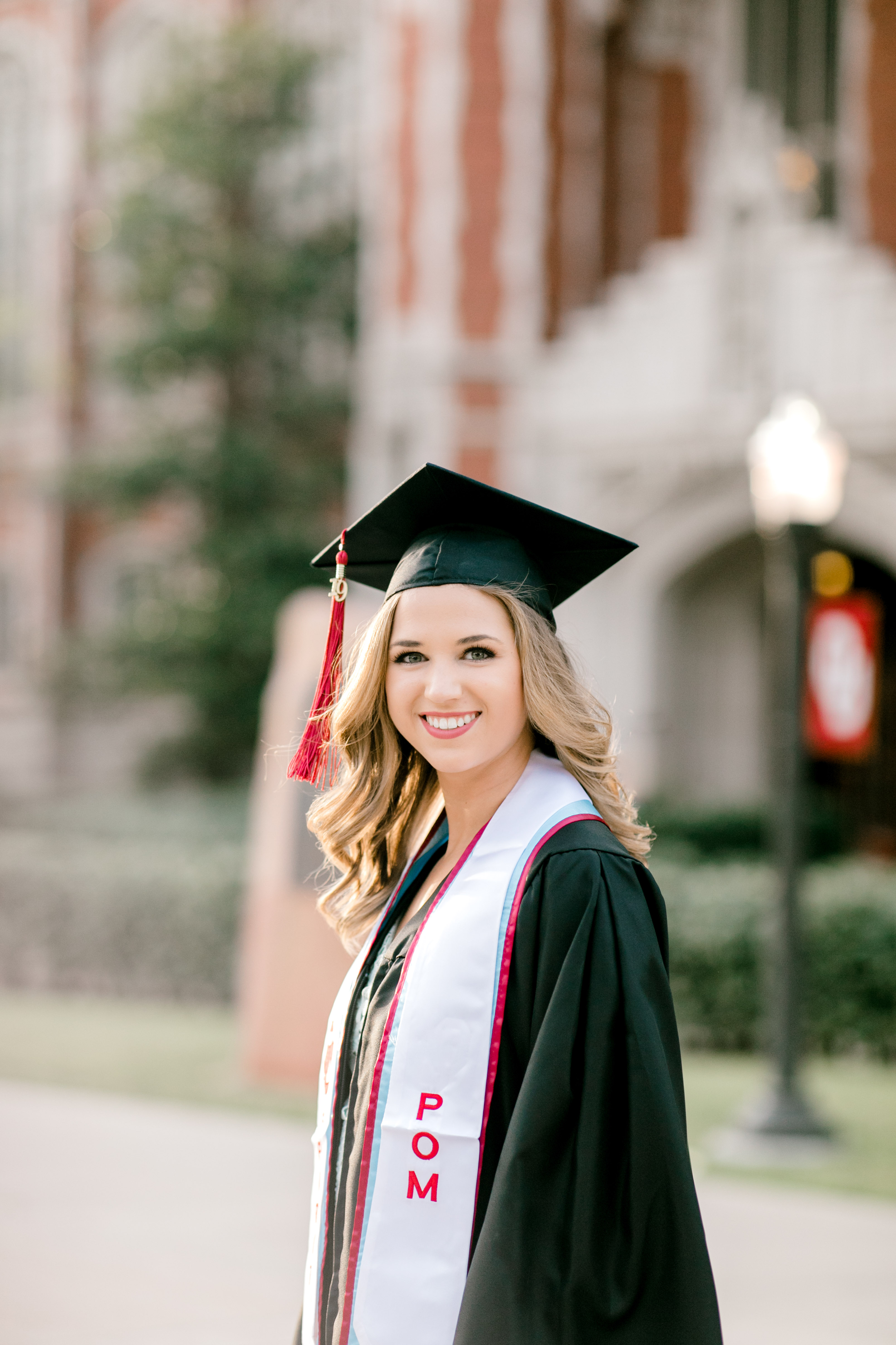 ou senior poses in front of bizzell library with graduation gearup for norman senior photographer