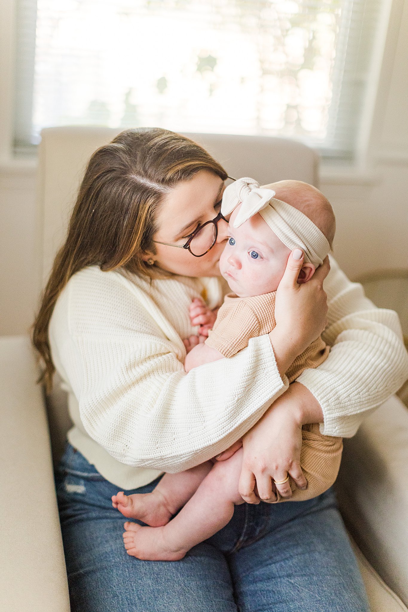 mom kisses cheek of infant daughter during in home family photos in bartlesville ok