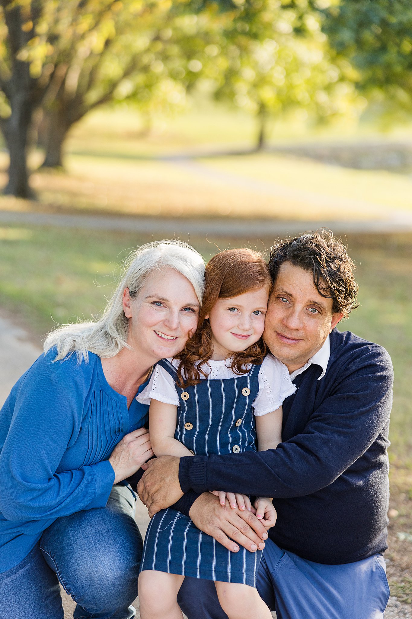 mom, dad, and daughter smile at camera for bartlesville mini session photographer