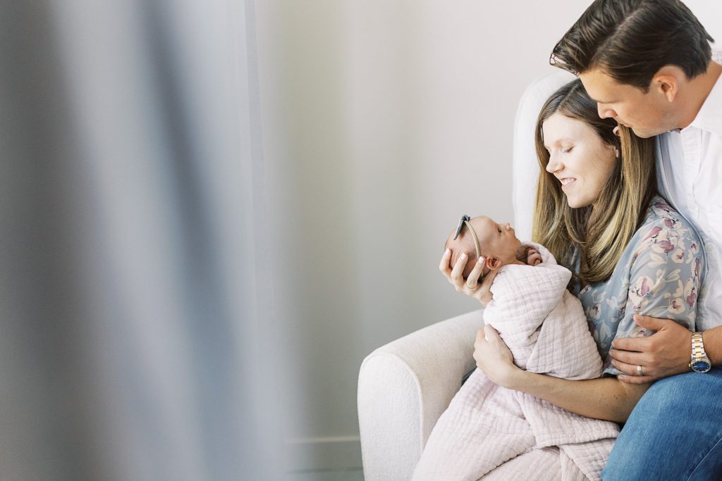 Mom and dad sit with baby during in home lifestyle newborn photography session