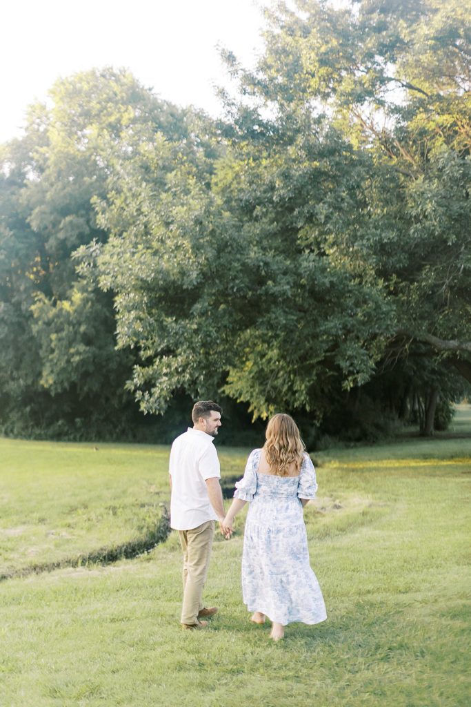 Man and woman walk in a Bartlesville Oklahoma park for maternity photos