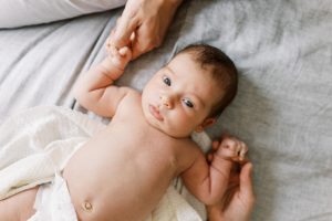 Newborn baby lays on bed while looking up at camera for lifestyle newborn photography OKC session