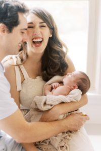 Mom laughs during newborn and family photography session