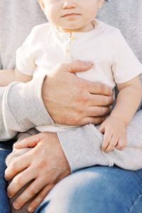 Father holds young toddler to his chest during family portraits