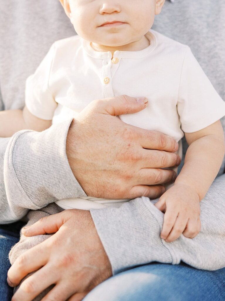 Father holds young toddler to his chest during family portraits