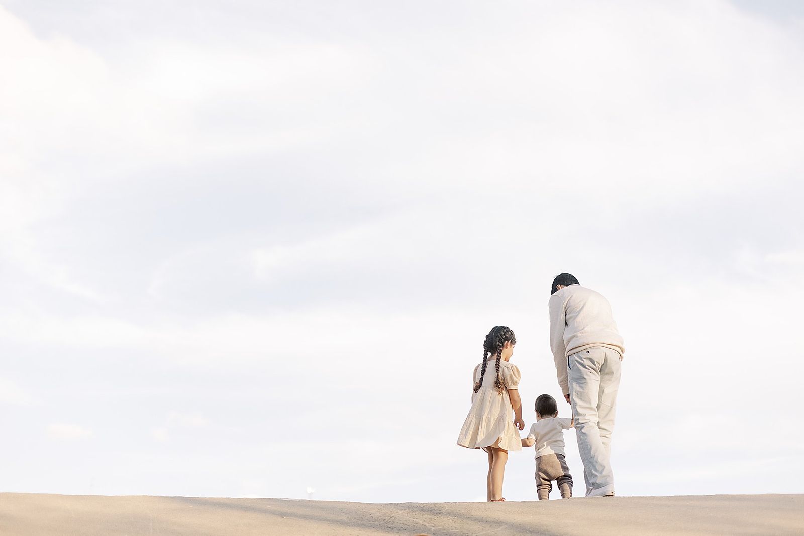Dad stands with daughter and young toddler, facing away from camera