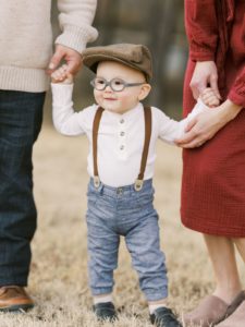 Toddler holding mom and dad hands during family portraits