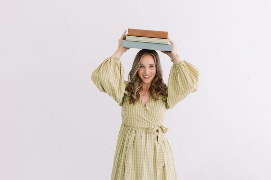 tulsa full-service photography experiences from melanie foster, holding a stack of keepsake albums and balancing on her head.